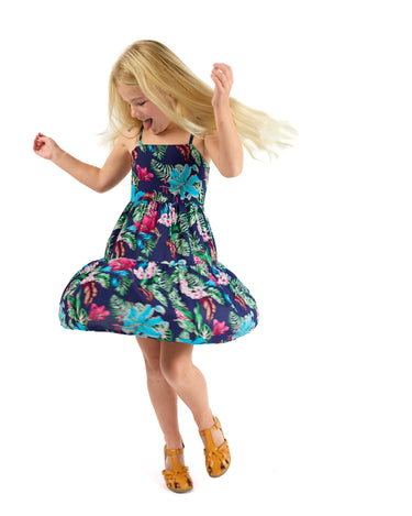 Young girl wearing a cute colorful floral fall school dress on a white background