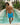 Man in blue swim shorts standing by a pool with palm trees in the background