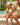 Man and child in matching colorful outfits sitting by a pool with drinks.