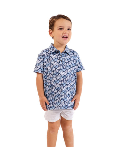 Child wearing a blue floral shirt and white shorts on a white background