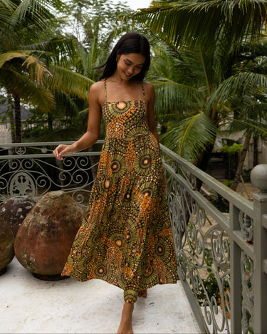 Woman in a african tribal patterned resort vacation dress standing on a balcony with palm trees in the background